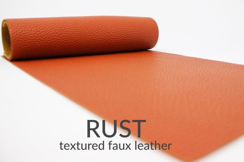 May include: A roll of textured faux leather in a rust colour. The leather has a pebbled texture. RUST textured faux leather.