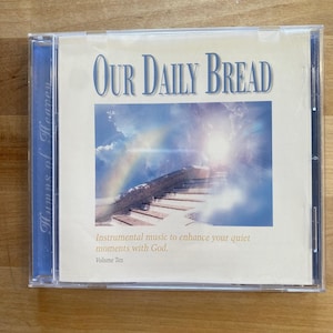 May include: A CD case with the title "Our Daily Bread" in blue lettering. The cover art features a stairway to heaven with a rainbow and clouds. The text "Hymns of Heaven" is on the side. The text "Instrumental music to enhance your quiet moments with God. Volume Ten" is also visible.