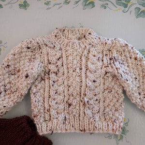 Doll sweater with cable pattern knitted in.