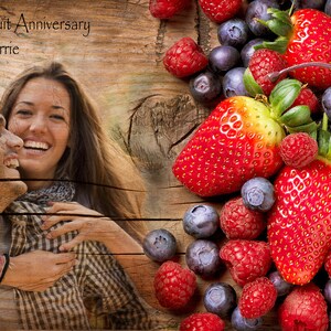 May include: A couple, Sam and Carrie, are pictured in front of a wooden background with a fruit border. The border includes strawberries, raspberries, blueberries, and a cherry.