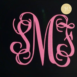 Pu&ograve; includere: Lettera M monogramma rosa glitter con volute decorative. La lettera &egrave; su uno sfondo nero.