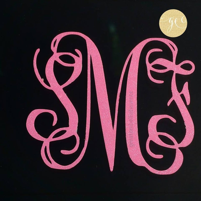 Pu&ograve; includere: Lettera M monogramma rosa glitter con volute decorative. La lettera &egrave; su uno sfondo nero.