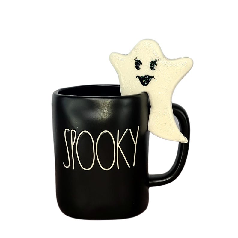 K&ouml;nnte beinhalten: Schwarze Keramiktasse mit dem Wort "SPOOKY" in wei&szlig;en Buchstaben. Ein wei&szlig;er Geist mit Glitzeraugen schaut aus der Tasse.