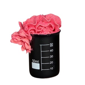 May include: A black graduated cylinder with pink glitter slime inside. The cylinder has markings for 50ml, 40ml, 30ml, 20ml, and 10ml.
