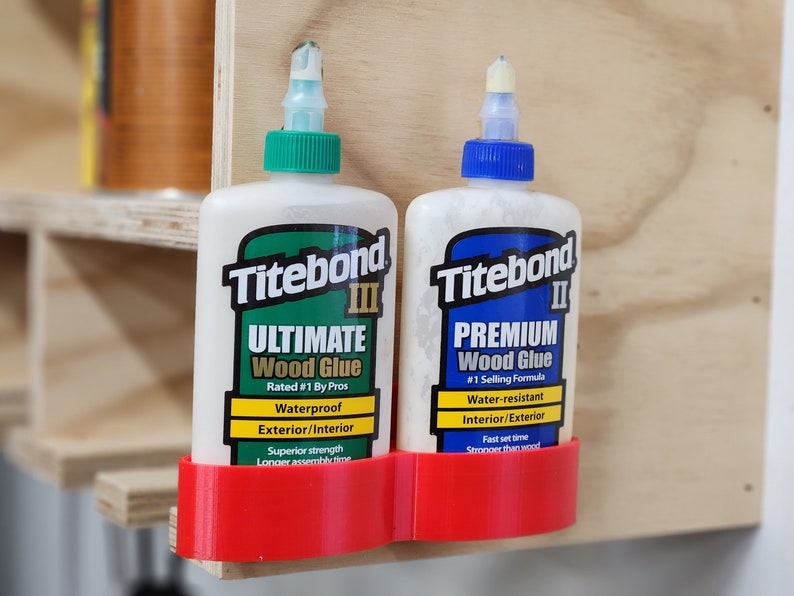 May include: Two bottles of Titebond wood glue, one labeled "Ultimate" and the other labeled "Premium", are held in a red plastic holder mounted on a wooden surface.