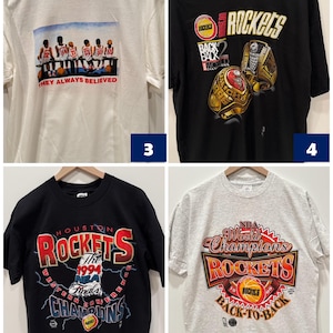 May include: Four different Houston Rockets t-shirts. The first is white with a picture of the team and the text "They Always Believed". The second is black with a picture of two championship rings and the text "Back 2 Back World Champions". The third is black with the text "Houston Rockets" and "1994 NBA Finals Western Conference Champions". The fourth is gray with the text "NBA World Champions Houston Rockets Back-to-Back".