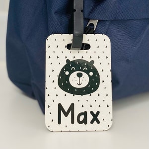 Puede incluir: Etiqueta de equipaje blanca con una ilustraci&oacute;n de oso en blanco y negro y el nombre Max impreso en negro.