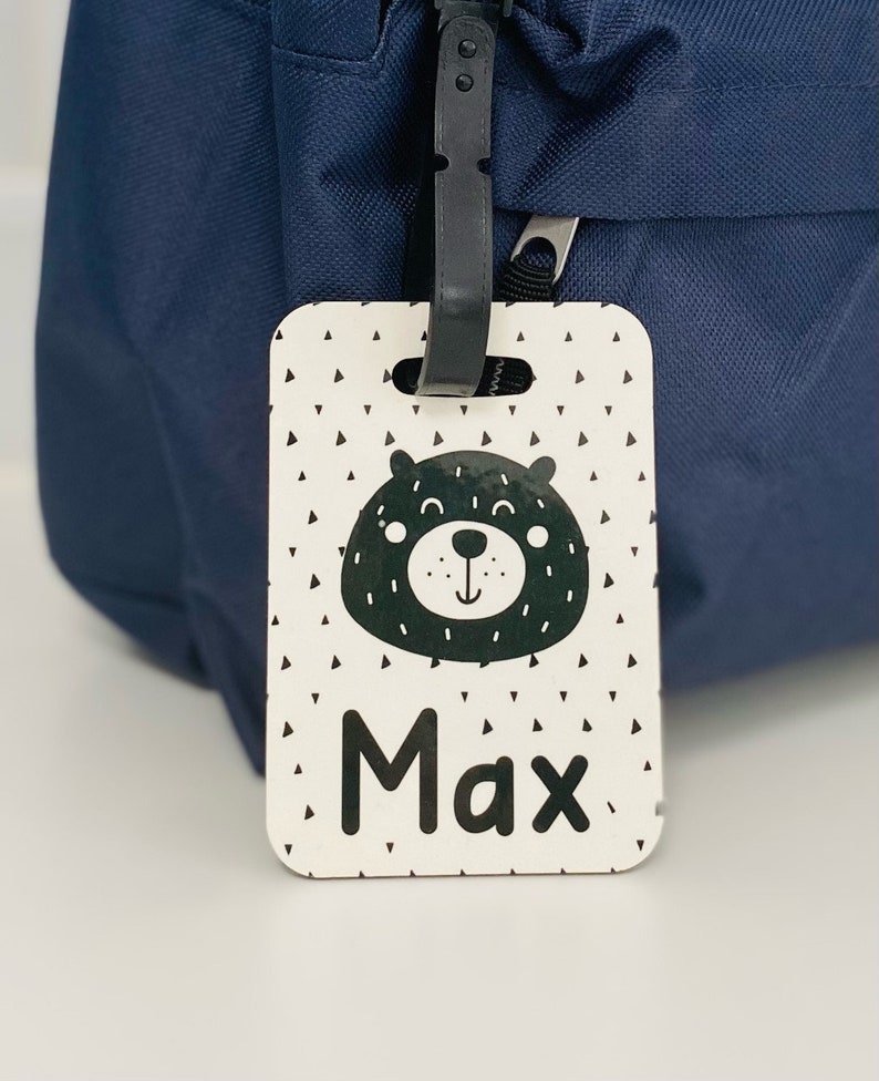 Puede incluir: Etiqueta de equipaje blanca con una ilustraci&oacute;n de oso en blanco y negro y el nombre Max impreso en negro.