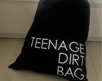 Puede incluir: Bolsa de lavandería negra con texto blanco que dice "Teenage Dirt Bag".
