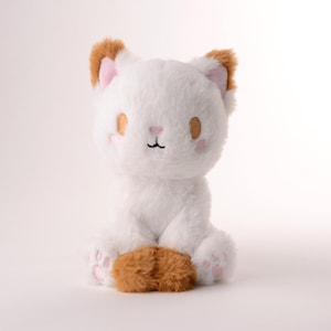 Może przedstawiać: Pluszowa zabawka w kształcie białego kota z brązowymi uszami i łapami. Kot ma wyszywane oczy i różowy nos.