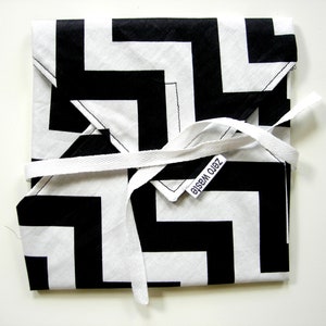 Op de afbeelding: Een zwart-witte stoffen cadeauverpakking met een chevron-patroon. De stof is vastgebonden met een wit lint en heeft een label met de tekst "Zero Waste".