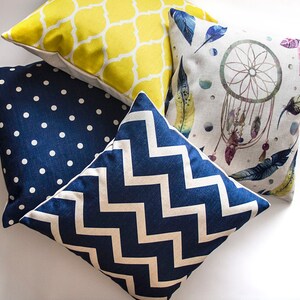 May include: Four decorative throw pillows with different patterns. One pillow has a yellow geometric pattern, one has a blue and white chevron pattern, one has a blue polka dot pattern, and one has a white background with a watercolor dreamcatcher and feathers.