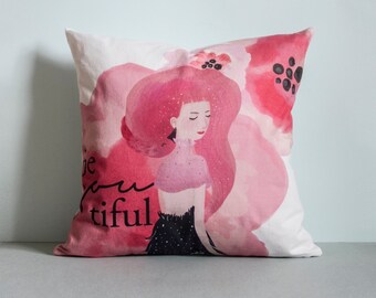 May include: A white pillow with a pink and black watercolor design featuring a woman with long pink hair and the text "Be youtiful".