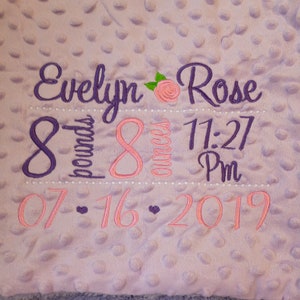 May include: Purple and pink embroidered baby blanket with the name Evelyn Rose, birth date 07-16-2019, time 11:27 PM, weight 8 pounds, and 8 ounces.