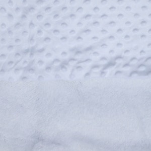 May include: A close-up of a white, plush blanket with a textured, dotted pattern. The blanket is soft and fluffy, and it appears to be made of a high-quality material.