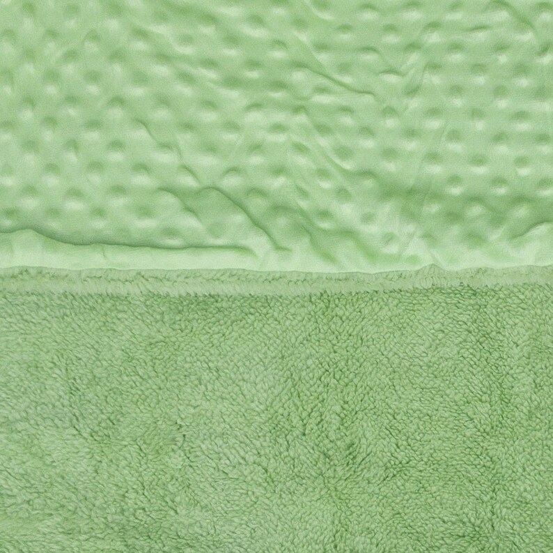 May include: A soft, green blanket with a textured, quilted top and a fluffy, plush bottom.