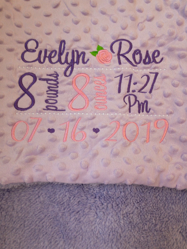 May include: Purple and pink embroidered baby blanket with the name Evelyn Rose, birth date 07-16-2019, time 11:27 PM, weight 8 pounds, and 8 ounces.