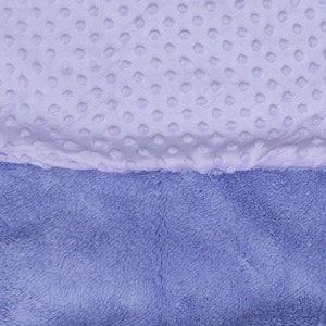 May include: A soft, two-toned baby blanket with a light purple side featuring a textured dot pattern and a darker purple side with a fuzzy texture.