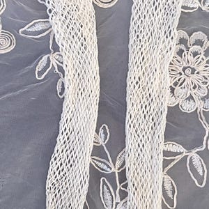 Puede incluir: Un par de medias de color crema con tejido abierto. Las medias est&aacute;n hechas de un material similar a una red y se muestran sobre un fondo de tela bordada blanca con motivos florales y de hojas. Las medias son un accesorio de moda.