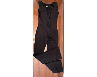Black catsuit with front zipper, sleeveless with bootcut leg.