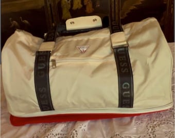 Bolsa Guess branca/creme, com compartimento extra vermelho na parte inferior.