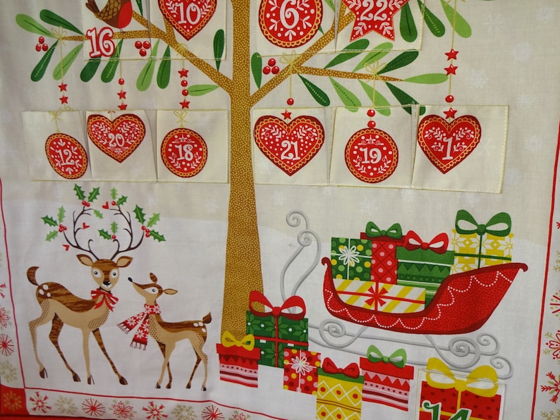 Puede incluir: Un calendario de adviento navide&ntilde;o con un &aacute;rbol, renos y un trineo lleno de regalos. El &aacute;rbol tiene 24 bolsillos numerados, cada uno con una abertura en forma de coraz&oacute;n. Los renos son marrones con lazos rojos y cuernos. El trineo es rojo con un borde blanco y est&aacute; lleno de regalos envueltos de colores.