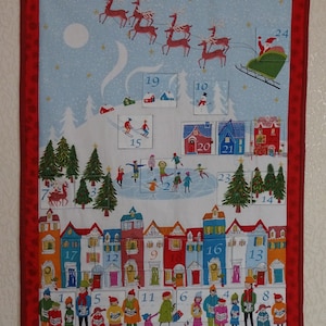 Puede incluir: Un calendario de adviento navideño colorido con una escena de pueblo de invierno. El calendario presenta una fila de casas con puertas numeradas, un paisaje nevado con un lago congelado y un trineo tirado por renos volando en el cielo. Los números del 1 al 24 son visibles en el calendario.