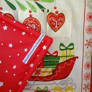 Puede incluir: Tela roja con estrellas blancas y una etiqueta azul que dice "BlueButterflyBunting". La tela est&aacute; doblada sobre una tela blanca con un dise&ntilde;o de calendario de adviento navide&ntilde;o. El calendario tiene un coraz&oacute;n rojo con el n&uacute;mero "1" en &eacute;l, un adorno rojo con el n&uacute;mero "19" en &eacute;l y un trineo rojo con regalos.