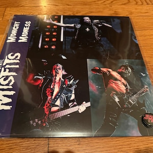 May include: The Original Misfits "Midnight Madness" vinyl record album. The album cover features images of the band performing live. The album is in a plastic sleeve. A Teenage From Mars pin is visible.
