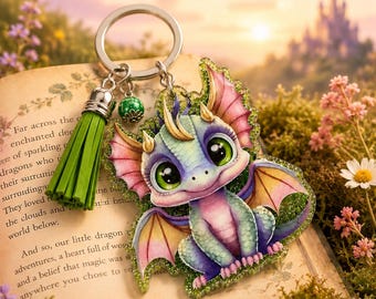 May include: A keychain featuring a glittery, illustrated baby dragon with large green eyes, purple and teal scales, and pink-tipped wings. It includes a bright green leather tassel and a small green bead attached to a silver-toned metal ring.