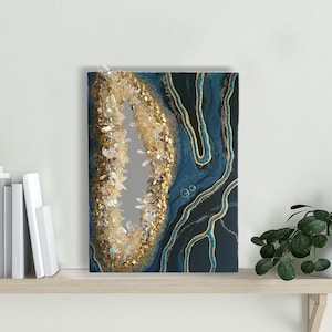 May include: Abstract art painting with a geode design. The geode is filled with gold and white crystals and is set against a dark blue background with gold accents.