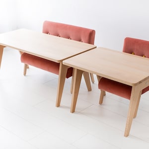 May include: A light wood table and bench set featuring a rectangular tabletop with rounded corners and angled legs. The bench has a tufted backrest upholstered in a dusty rose velvet fabric with visible button detailing and a matching seat cushion.