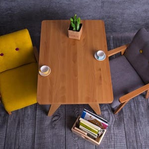 Peut inclure: Vue de dessus d'une petite table en bois avec deux fauteuils. Le fauteuil jaune a deux boutons violets, et le fauteuil gris a deux boutons jaunes. Deux tasses &agrave; th&eacute; et une petite plante sont sur la table.