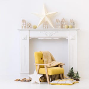Peut inclure: Un manteau de chemin&eacute;e blanc avec des maisons en bois d&eacute;coratives, une grande &eacute;toile et de petits arbres verts. Un fauteuil jaune avec une couverture beige et un coussin en forme d'&eacute;toile sont devant. Une &eacute;toile en bois est au sol.