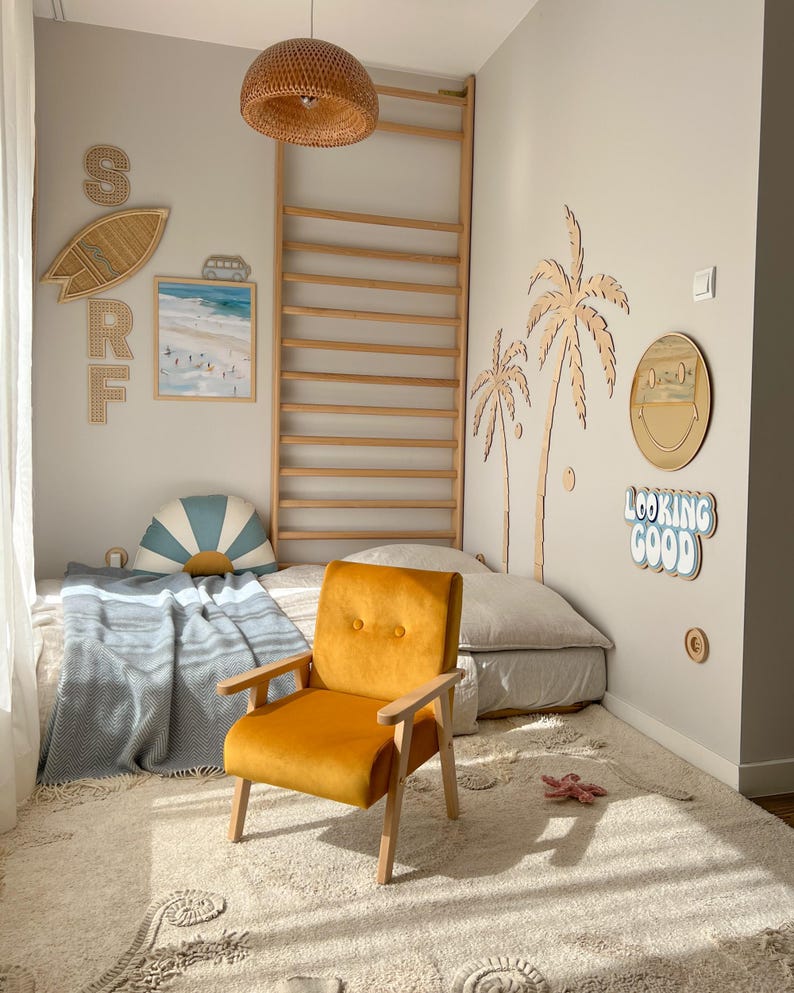 Peut inclure: Chambre d'enfant sur le th&egrave;me de la plage. Un fauteuil en velours orange avec des bras et des pieds en bois est pos&eacute; sur un tapis cr&egrave;me. D&eacute;corations murales : planche de surf, palmiers et l'expression "Looking Good".