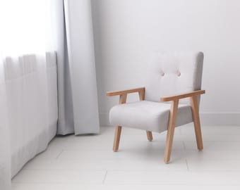 Un pequeño asiento infantil de estilo retro en color gris claro.