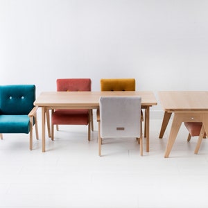 Peut inclure: Une table de salle &agrave; manger en bois clair avec quatre chaises de couleurs vari&eacute;es : turquoise, rouille, moutarde et rose. Les chaises ont des pieds et des dossiers en bois, avec des assises rembourr&eacute;es. Design moderne.