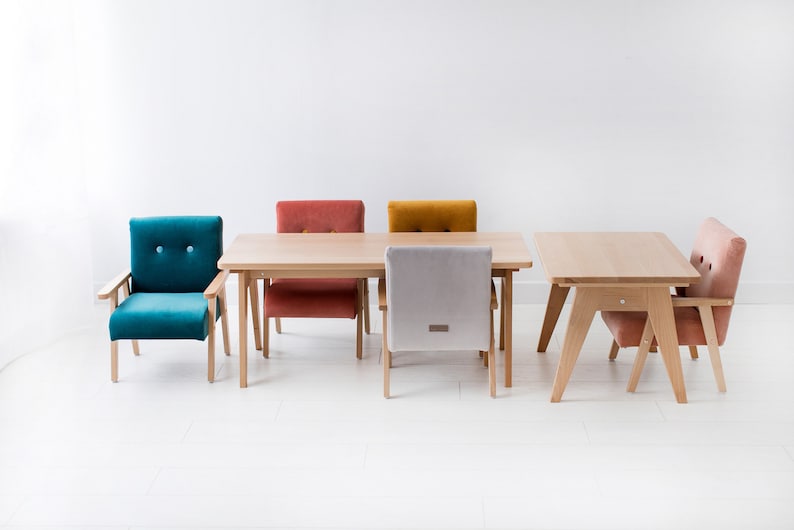 Peut inclure: Une table de salle &agrave; manger en bois clair avec quatre chaises de couleurs vari&eacute;es : turquoise, rouille, moutarde et rose. Les chaises ont des pieds et des dossiers en bois, avec des assises rembourr&eacute;es. Design moderne.