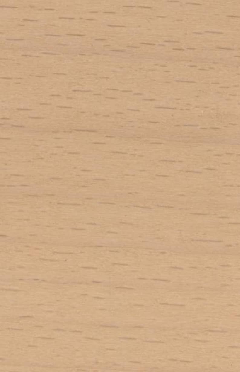 May include: A light tan wood grain surface featuring a smooth texture with subtle, elongated dark brown flecks and horizontal lines distributed across the material, showcasing the natural pattern and organic appearance of the wood grain.