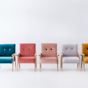 Peut inclure: Cinq fauteuils color&eacute;s align&eacute;s. Chaque fauteuil a une structure en bois et une assise et un dossier en peluche capitonn&eacute;s. Les couleurs incluent le teal, le corail, le rose clair, le gris et le jaune moutarde. Fond blanc.