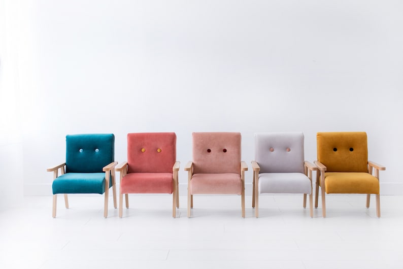 Peut inclure: Cinq fauteuils color&eacute;s align&eacute;s. Chaque fauteuil a une structure en bois et une assise et un dossier en peluche capitonn&eacute;s. Les couleurs incluent le teal, le corail, le rose clair, le gris et le jaune moutarde. Fond blanc.