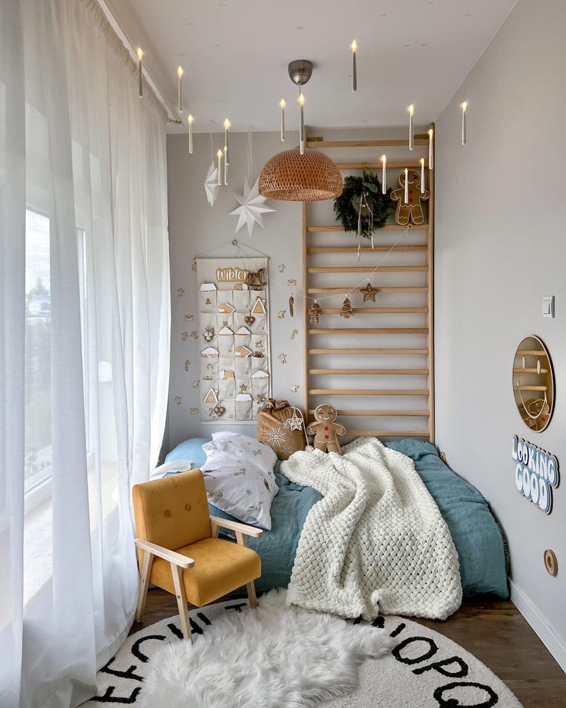 Peut inclure: Une chambre d&eacute;cor&eacute;e pour No&euml;l avec un lit bleu canard, une chaise moutarde et un tapis blanc duveteux. Des bougies d&eacute;coratives sont suspendues au plafond. Une &eacute;chelle en bois est orn&eacute;e de d&eacute;corations de No&euml;l.