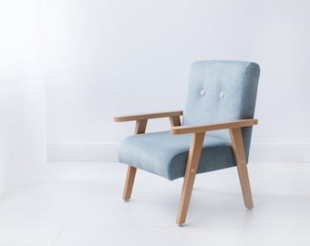 Un sillón pequeño, gris y menta para un niño, un sillón con laterales de madera en la habitación de un niño.