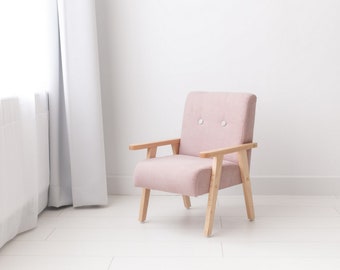 Un pequeño sillón de bebé en color rosa pastel polvoriento, tejido de terciopelo, un sillón con laterales de madera en una habitación infantil, un regalo para niños.