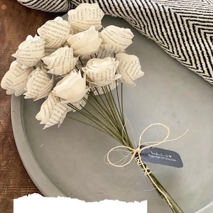 May include: A bouquet of paper roses made from book pages, tied with twine and a small gift tag that reads "handmade with love, Pageturner Designs".