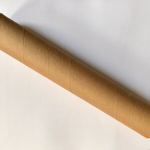 Puede incluir: Un tubo de env&iacute;o de cart&oacute;n marr&oacute;n con tapas blancas.