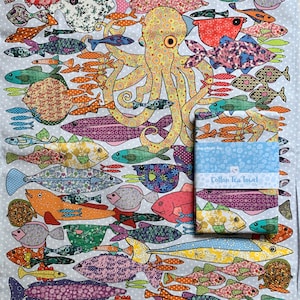 May include: A colorful cotton tea towel with a whimsical design of an octopus surrounded by various fish. The towel features a blue background with white polka dots and a border of brown and yellow shells. The text "Cotton Tea Towel" is printed on the towel.