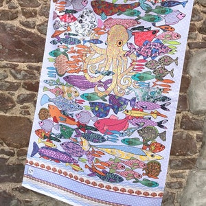 May include: A white tea towel with a colorful design of an octopus surrounded by fish. The fish are all different shapes, sizes, and colors. The octopus is yellow with brown spots and has eight tentacles. The tea towel has a blue border with a white polka dot pattern.