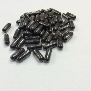 May include: A large pile of dark brown capsules on a white surface.