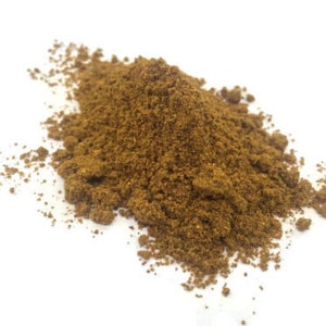May include: A pile of brown ground spices on a white background.